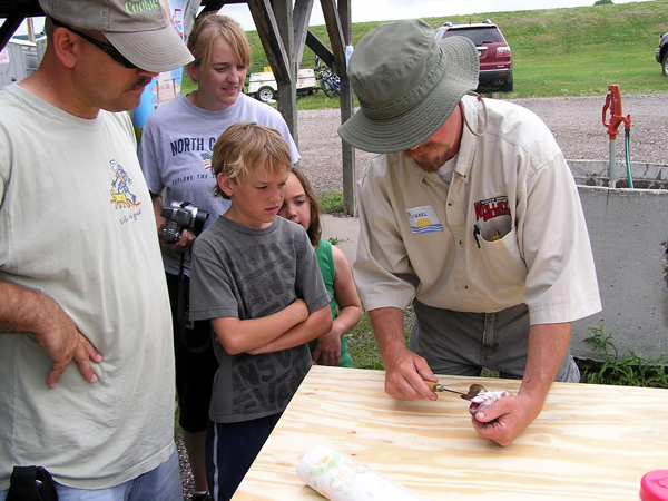Michael Johnson demonstrates how to clean a trout to a couple successful anglers at the EAFB Party